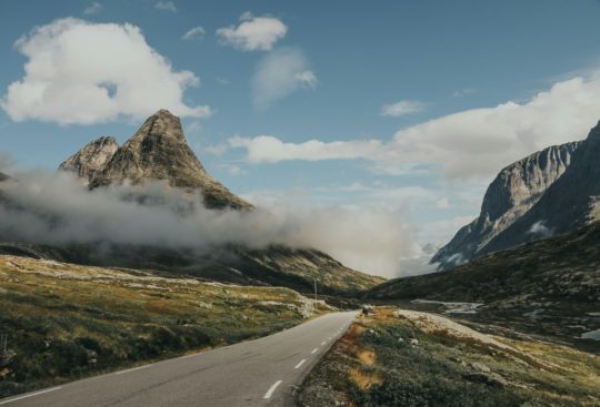 Asfaltert vei som går gjennom et mektig norsk fjellandskap.